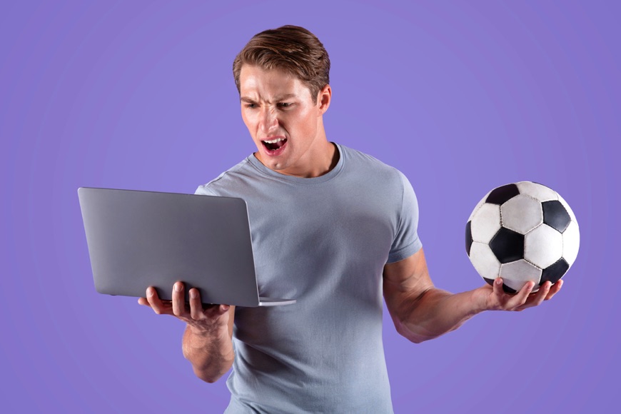 Disappointed man at laptop with football
